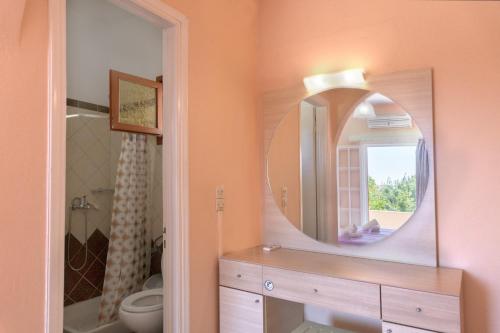 uma casa de banho com um espelho, um lavatório e um WC. em Dora Apartment Pagoi 2 em Agios Georgios Pagon