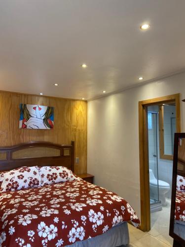 a bedroom with a bed with a red comforter at Hostal Maitencillo Norte in Maitencillo