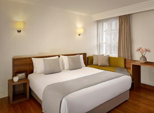 a bedroom with a large white bed and a couch at Citadines South Kensington London in London