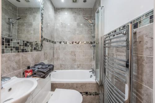 a bathroom with a tub and a toilet and a sink at Stylish Central Edinburgh Abode in Edinburgh