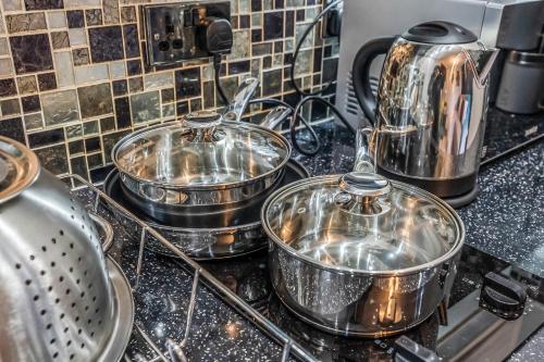 three pots and pans on a stove in a kitchen at Stylish Central Edinburgh Abode in Edinburgh