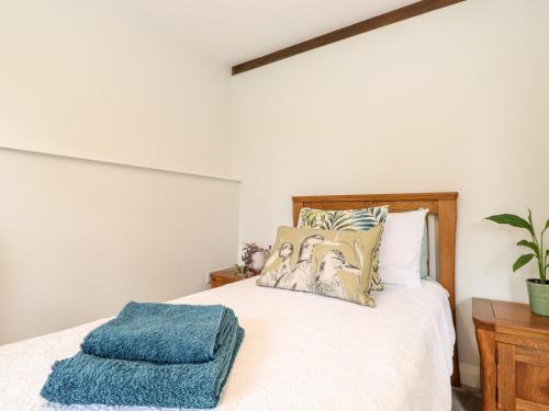 a bedroom with a bed with a blue towel on it at Monkey Puzzle Cottage in Sedbergh