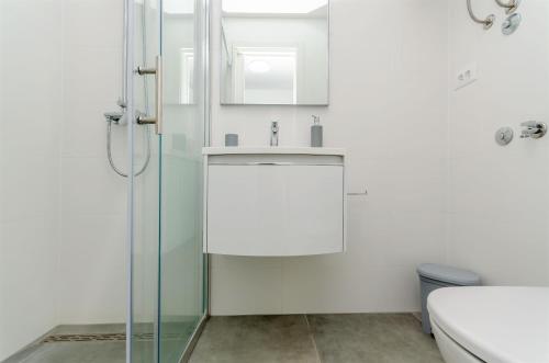 een badkamer met een wastafel en een douche bij Apartments Milan in Rogoznica