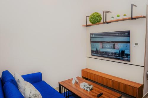 a living room with a blue couch and a tv at VOGO Grand Hotel Formerly Best Western Plus Hotel Dubai Academic City in Dubai