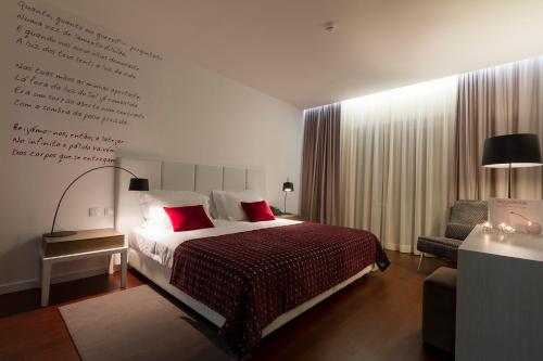 a bedroom with a bed with red pillows and a writing wall at Hotel Vila D'Óbidos in Óbidos