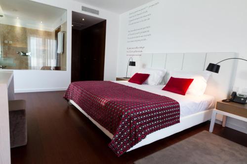 a bedroom with a large white bed with red pillows at Hotel Vila D'Óbidos in Óbidos