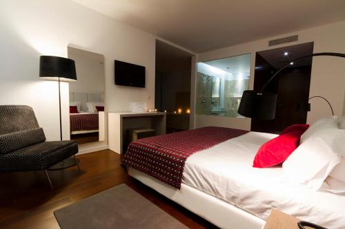 a bedroom with a bed and a chair and a television at Hotel Vila D'Óbidos in Óbidos