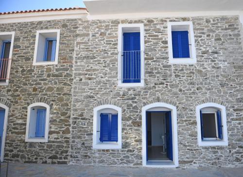 a brick building with blue shutters on it at Armenistis appartments with a view in Armenistis