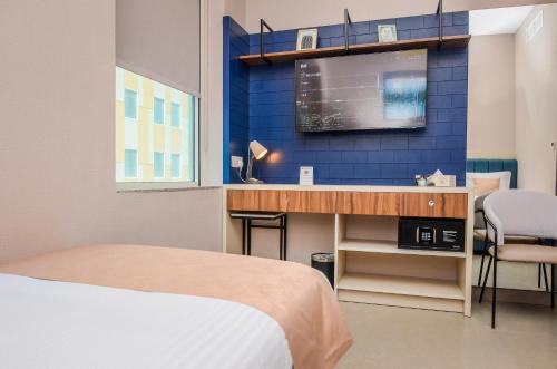 a bedroom with a bed and a desk with a tv at VOGO Grand Hotel Formerly Best Western Plus Hotel Dubai Academic City in Dubai