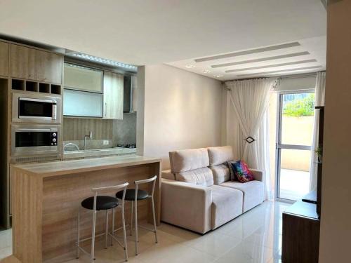 a kitchen with a bar and a couch in a room at Apartamento Villa Nova Master Collection in Passo Fundo