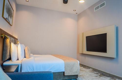 a hotel room with a bed and a tv at VOGO Grand Hotel Formerly Best Western Plus Hotel Dubai Academic City in Dubai