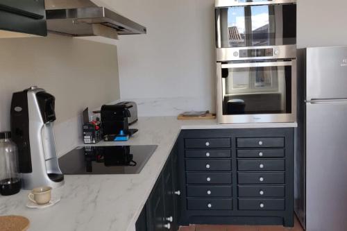 a kitchen with a stove top oven and a microwave at La Maison de Colette - Coeur de village in Cuxac-dʼAude