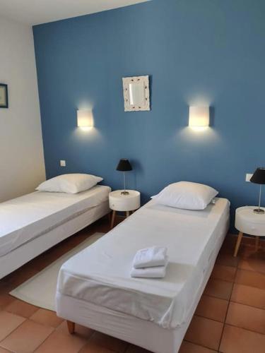 - 2 lits dans une chambre avec un mur bleu dans l'établissement La Maison de Colette - Coeur de village, à Cuxac-dʼAude