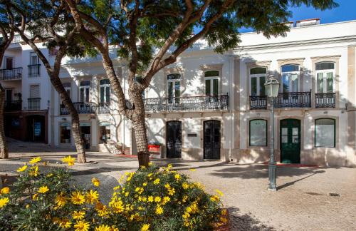 een wit gebouw met gele bloemen ervoor bij Casa Margô in Lagos