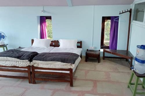 a bedroom with a large bed with purple curtains at BAANZ CABIN - managed by The Silver Oak Place in Pithorāgarh