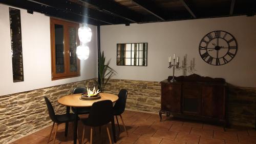 a dining room with a table and a clock on the wall at "O Cabazo de Reinante" in Barreiros