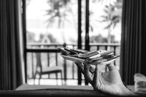 a person holding a plate of keys in front of a window at Chill House make a Good Story with infinite Ocean Surf and Stay in Weligama