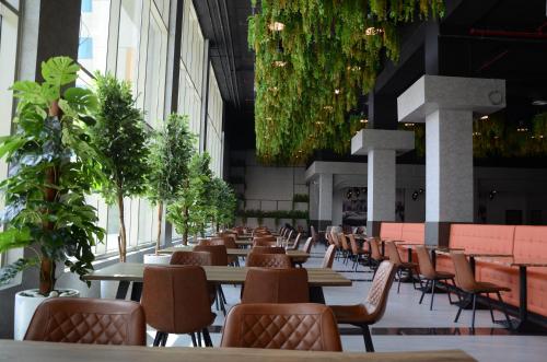 a row of tables and chairs in a building with plants at VOGO Grand Hotel Formerly Best Western Plus Hotel Dubai Academic City in Dubai
