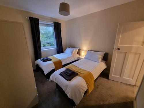 two beds in a room with a window at Lovely 3 bed apartment in Aberdeen in Aberdeen