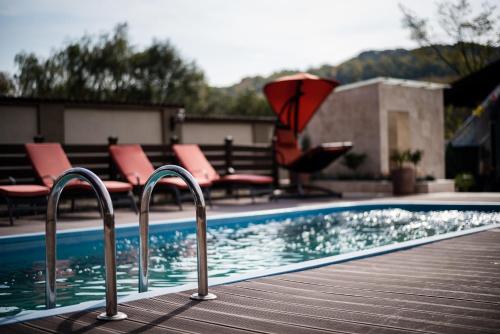 a swimming pool with metal hand rails next to some chairs at Gasthaus Hundorf in Viişoara