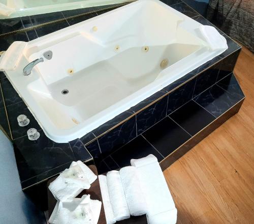 a white bath tub in a bathroom with black tiles at Motel Bonsoir in Joliette