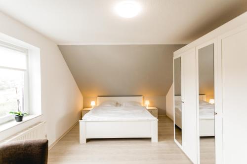 a bedroom with a white bed and a mirror at Strandperle Alexander in Hofe