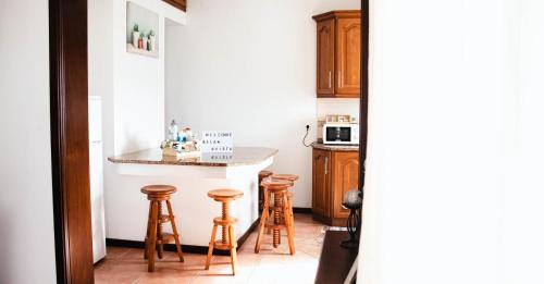 a kitchen with wooden stools and a counter top at Apartamento Bela Vista Ilha Terceira in Feteira