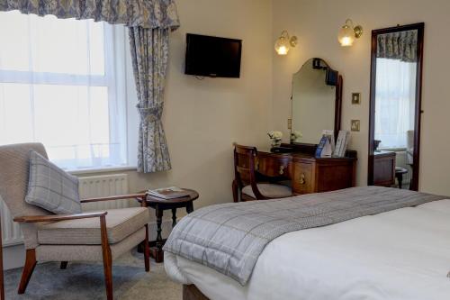a bedroom with a bed and a chair and a mirror at The Lansdowne, Eastbourne in Eastbourne