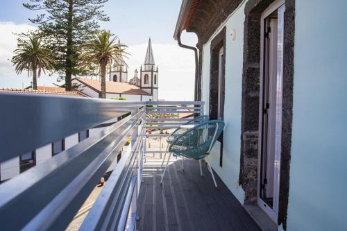 a bench on the balcony of a building with a church at My Bed in pico in Madalena
