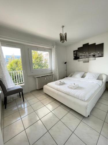 a white bedroom with a bed and a chair at Résidence les Menestrels in Annemasse