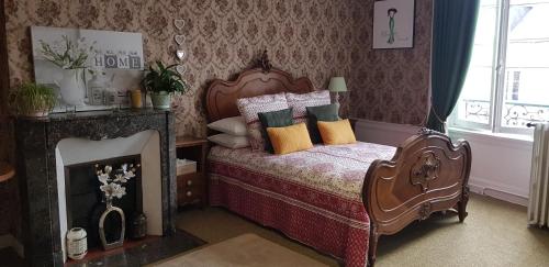 una camera da letto con letto, cuscini e camino di Maison de Berry Bed & Breakfast a Villedieu-les-Poëles