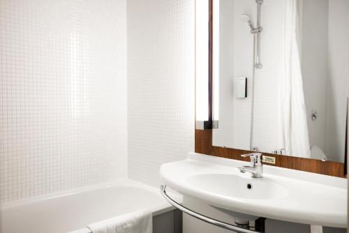 a white bathroom with a sink and a bath tub at Campanile Swindon in Swindon