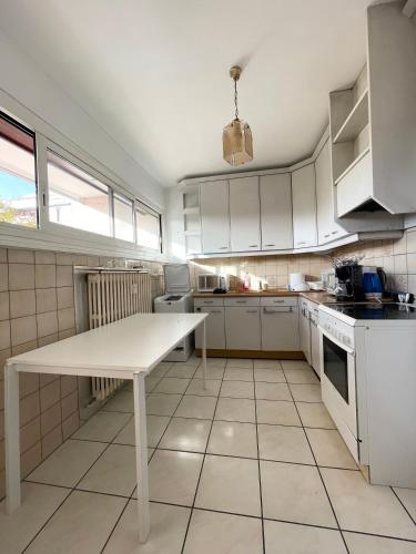 a kitchen with white cabinets and a white table at Résidence les Menestrels in Annemasse