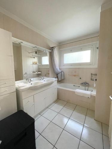 a white bathroom with a tub and a sink and a window at Résidence les Menestrels in Annemasse