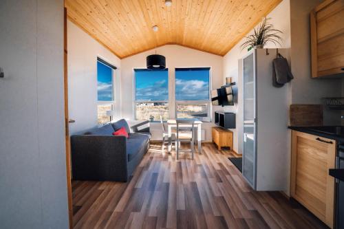 een keuken en een woonkamer met een bank en een tafel bij Blue View Cabin 6B With private hot tub in Reykholt