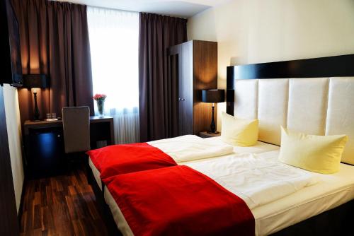 a bedroom with a large bed with a red blanket at Admiral Hotel in Frankfurt