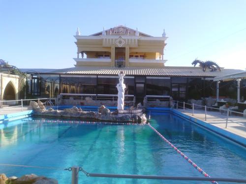 a swimming pool with a fountain in front of a building at Nouvelle in Oraiokastro