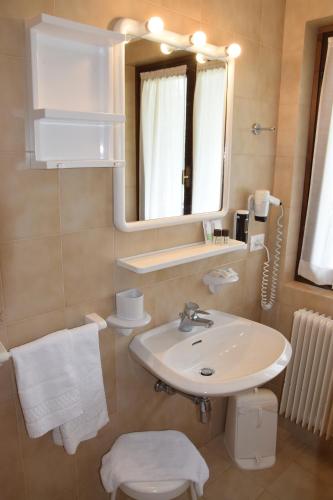 bagno con lavandino, specchio e servizi igienici di Hotel Ferrari a Pinzolo