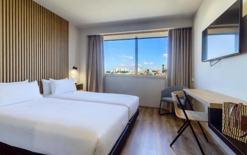 um quarto de hotel com duas camas e uma secretária e uma janela em room Select Porto no Porto