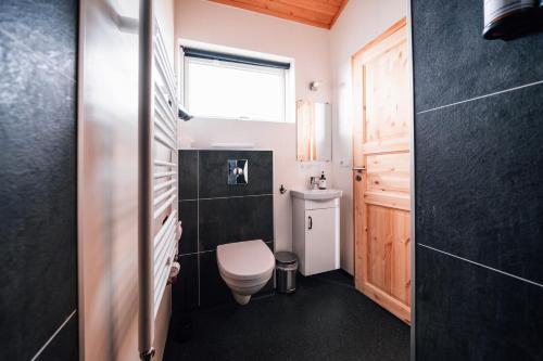 a small bathroom with a toilet and a window at Blue View Cabin 1B With private hot tub in Reykholt