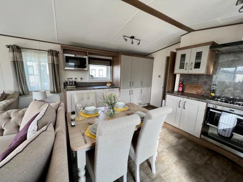 eine Küche und ein Esszimmer mit einem Tisch und einem Sofa in der Unterkunft Sunflower Hot Tub Lodge in South Cerney