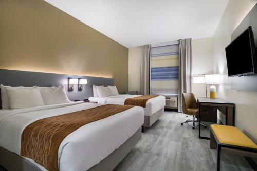 a hotel room with two beds and a desk at Comfort Inn & Suites Victoria North in Victoria