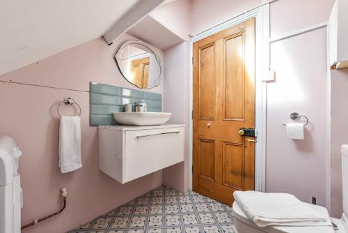 ein Badezimmer mit einem Waschbecken, einem WC und einem Spiegel in der Unterkunft Traditional 3-Bed Property in Pontcanna with Parking in Cardiff