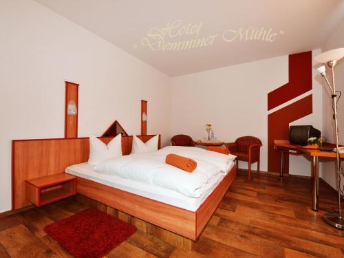 a bedroom with a bed and a desk and a television at Hotel Demminer Mühle in Demmin