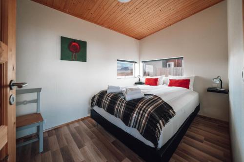 1 dormitorio con 1 cama grande con almohadas rojas en Blue View Cabin 4A With private hot tub, en Reykholt