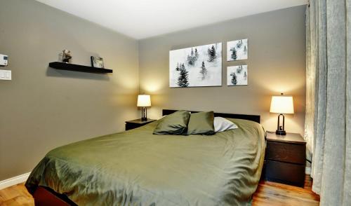 - une chambre avec un lit avec deux lampes et deux tables dans l'établissement Condo 105 33 Chemin du Hameau by Les Chalets Alpins, à Stoneham