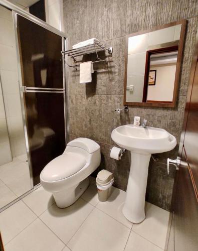 a bathroom with a toilet and a sink and a shower at Hotel - Bravo Grand Hotel in Quevedo