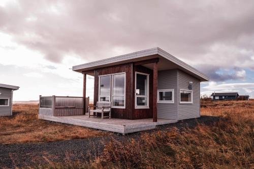 a small house with a deck in a field at Blue View Cabin 4B With private hot tub in Reykholt