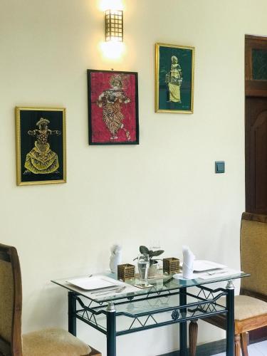 a glass table in a room with pictures on the wall at Tranquil Quarter in Kandy