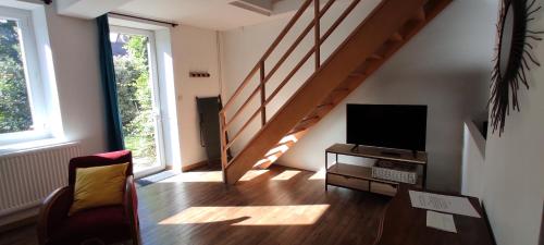 a living room with a staircase and a television at Le nid d'Eugénie in Blaudeix